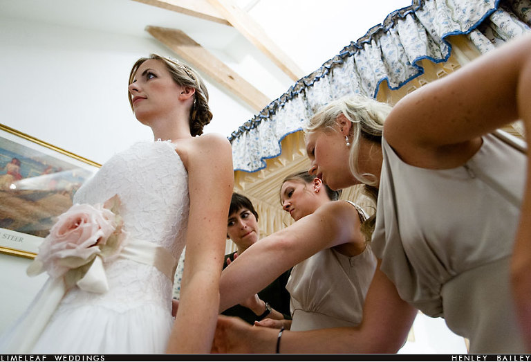 Bridesmaids helping bride in to her dress
