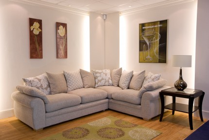 Room set up with cream fabric sofa corner group with cushions and corner tables