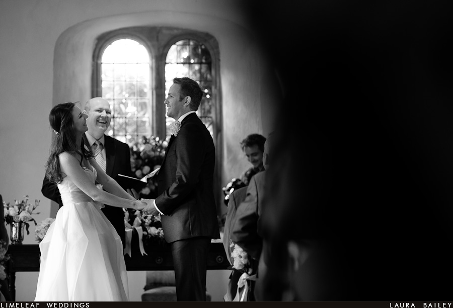 brympton-house-wedding-photography-120728-154225,_ Bride and groom hold hands and laugh during their wedding vows