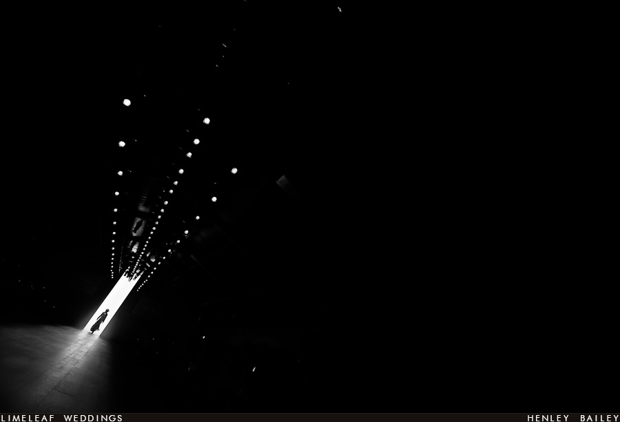 Silhouette of a model is framed by lights on the catwalk 