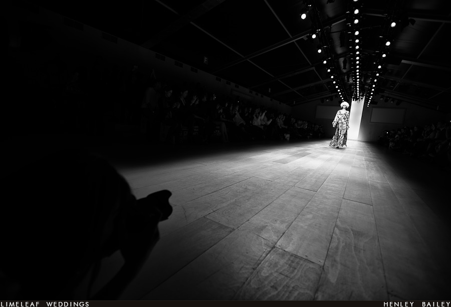 Model heads down the catwalk as a photographer waits at the end