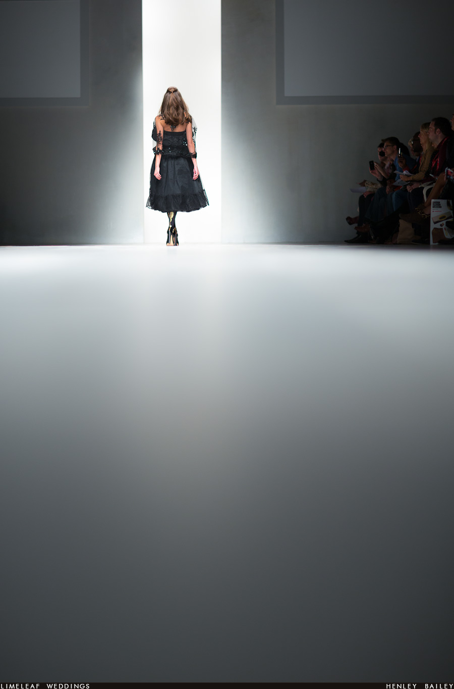 Model seen from behind heads back into the wings after her turn on the catwalk at fashion week