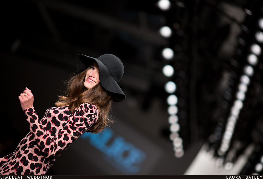 A model framed by the catwalk lights smiles at the waiting photographers at London Fashion Week