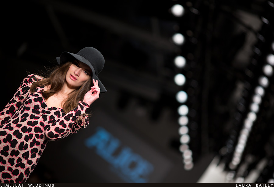 A model framed by the catwalk lights tips her hat to the waiting photographers at London Fashion Week
