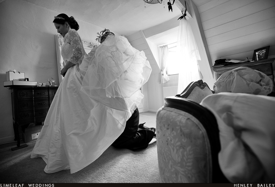 Bridesmaid is seen with only her legs showing under the brides wedding dress